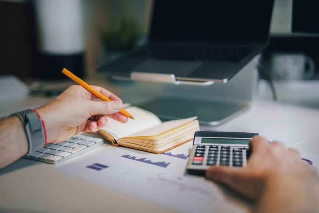 Como reduzir gastos mensais - pessoa organizando finanças e planilha de orçamento